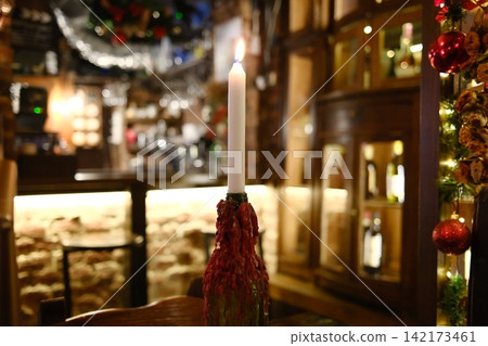 Warm candlelight glows inside a rustic tavern during Christmas season Warm candlelight glows inside a rustic tavern during Christmas season 142173461
