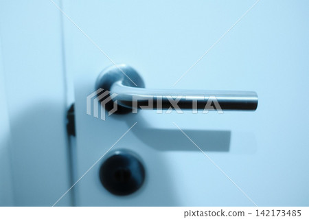 Modern metallic door handle on a white door Modern metallic door handle on a white door 142173485