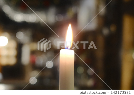 Golden candle flame glowing softly in the quiet night darkness Golden candle flame glowing softly in the quiet night darkness 142173581