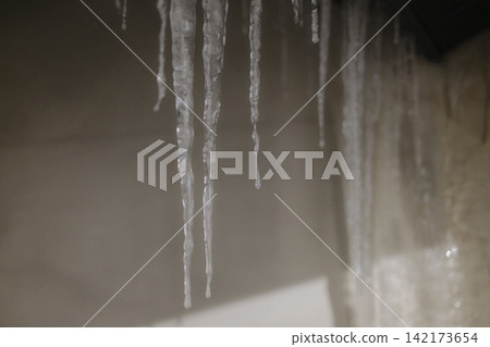 Sharp icicles hanging from a roof during a cold winter day Sharp icicles hanging from a roof during a cold winter day 142173654
