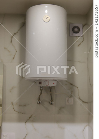 White electric water heater mounted on a tiled bathroom wall inside White electric water heater mounted on a tiled bathroom wall inside 142173657