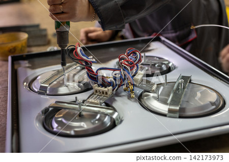 Hand using power tool on appliance wiring during repair Hand using power tool on appliance wiring during repair 142173973