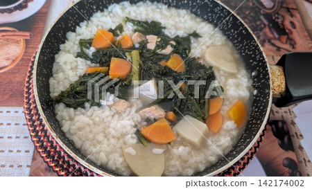 Homemade rice porridge with vegetables and meat served in a small frying pan Homemade rice porridge with vegetables and meat served in a small frying pan 142174002