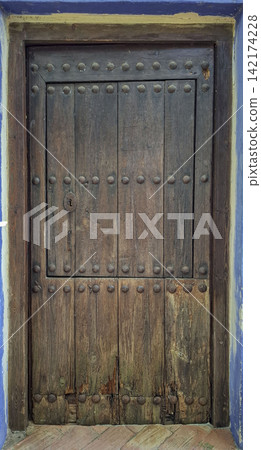 Rustic wooden door with metal studs and a vintage keyhole in an old building 142174228