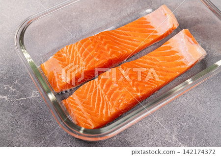 Two fresh raw salmon fillets in glass dish Two fresh raw salmon fillets in glass dish 142174372