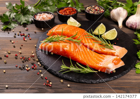 Fresh raw salmon fillets preparing with herbs and spices Fresh raw salmon fillets preparing with herbs and spices 142174377
