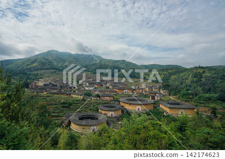 Fujian Tulou Village in Green Mountains Under Cloudy Sky Fujian Tulou Village in Green Mountains Under Cloudy Sky 142174623