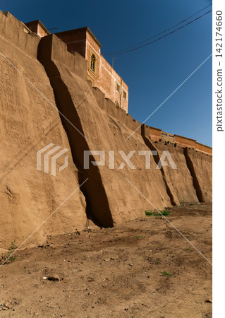 Adobe Fortress Wall and Traditional Desert Architecture Under Blue Sky Adobe Fortress Wall and Traditional Desert Architecture Under Blue Sky 142174660