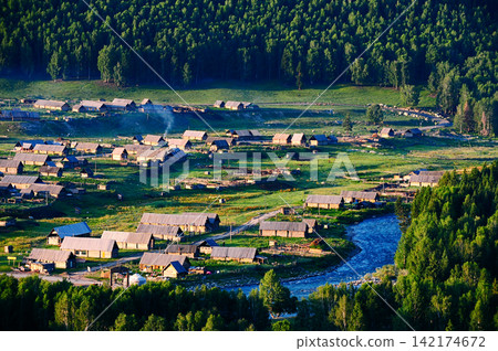 Rural Village by Mountain River in Lush Forest Landscape Rural Village by Mountain River in Lush Forest Landscape 142174672