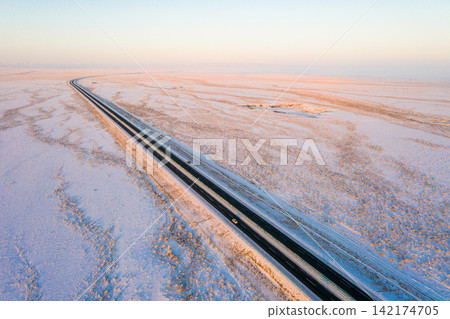 Aerial Highway Through Snowy Winter Plain at Sunrise Aerial Highway Through Snowy Winter Plain at Sunrise 142174705