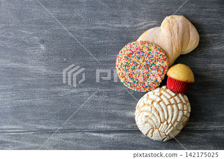 Mexican bakery, sweet bread on vintage gray table: shell, cupcake, bow tie, ear, biscuit with multicolored sprinkles 142175025