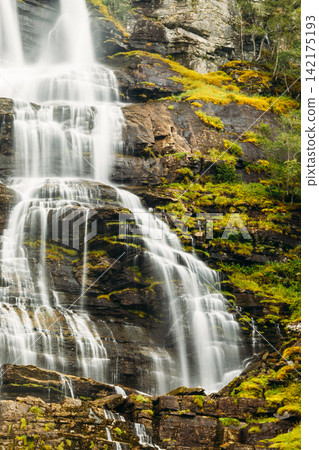Beautiful famous Tvindefossen Waterfall in Norway powerful, tall waterfall cascading down a rocky mountain face. Beautiful famous Tvindefossen Waterfall in Norway powerful, tall waterfall cascading down a rocky mountain face. 142175193