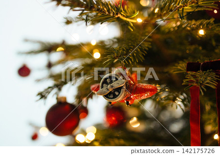 Vintage toy airplane ornament hanging on decorated Christmas tree Vintage toy airplane ornament hanging on decorated Christmas tree 142175726