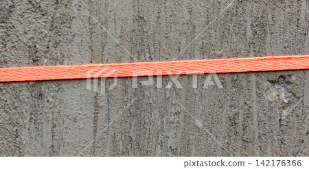 Bright orange ropes run across the rough gray concrete walls. Bright orange ropes run across the rough gray concrete walls. 142176366