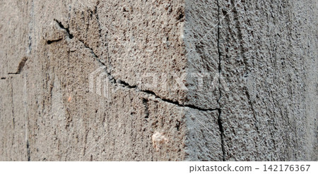 A cracked concrete pillar corner with a weathered plaster texture. A cracked concrete pillar corner with a weathered plaster texture. 142176367