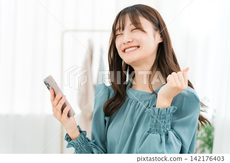 Smartphone, happy, smiling woman looking at her smartphone Smartphone, happy, smiling woman looking at her smartphone 142176403