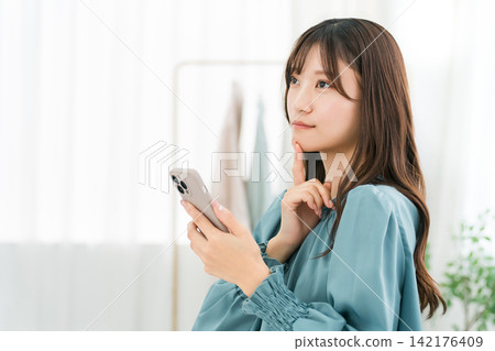 Young Asian business woman using a smartphone in the office Young Asian business woman using a smartphone in the office 142176409