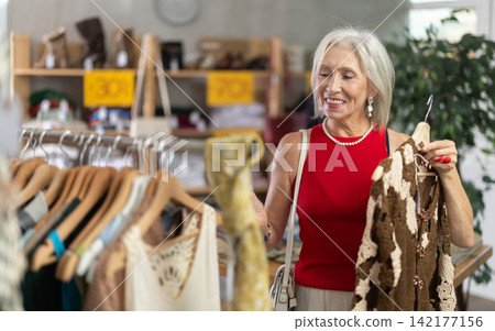 Elderly woman chooses cardigan in clothing store 142177156