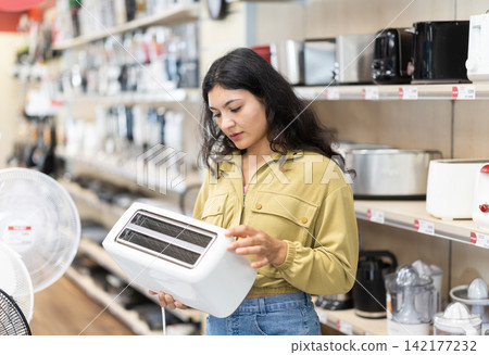 Latina woman looking at the assortment of toasters in the store Latina woman looking at the assortment of toasters in the store 142177232