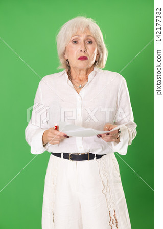Sad elderly woman with documents in front of green screen Sad elderly woman with documents in front of green screen 142177382