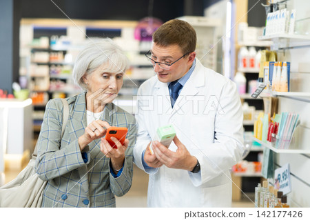 Man pharmacist talk to senior woman buyer and help to scan QR code on package Man pharmacist talk to senior woman buyer and help to scan QR code on package 142177426
