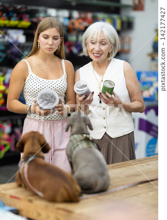 elderly woman stands in a pet store with a teenage girl and chooses food elderly woman stands in a pet store with a teenage girl and chooses food 142177427