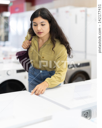 Latina woman came to a modern home appliance store, she choose a washing machine Latina woman came to a modern home appliance store, she choose a washing machine 142177431