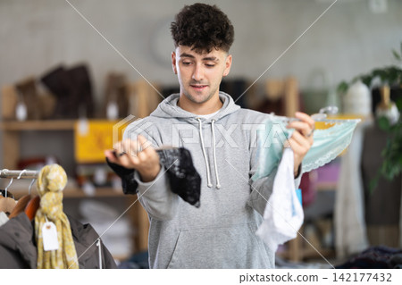 Young man chooses female panties in clothing store Young man chooses female panties in clothing store 142177432