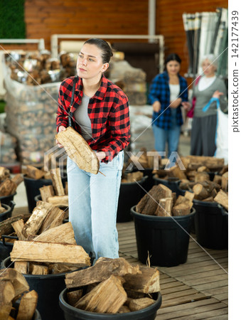 Young woman choosing firewood in store 142177439