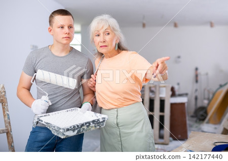 Senior woman discussing work details with teenager boy in constrcuction site Senior woman discussing work details with teenager boy in constrcuction site 142177440