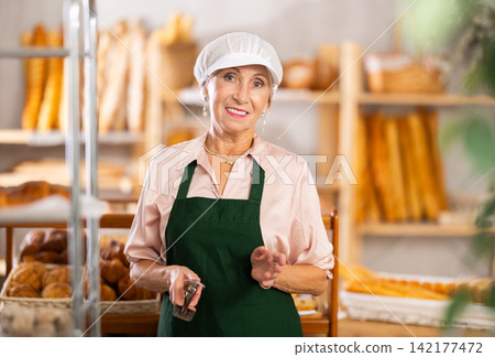 Portrait of professional elderly female baker in uniform in bakery Portrait of professional elderly female baker in uniform in bakery 142177472