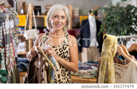 Elderly woman choosing summer clothes in store Elderly woman choosing summer clothes in store 142177479