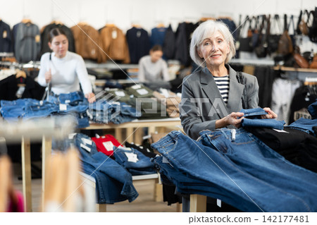 Elderly woman chooses jeans in store Elderly woman chooses jeans in store 142177481