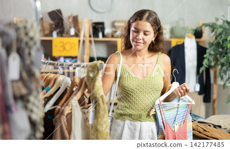 Young woman choosing summer clothes in store Young woman choosing summer clothes in store 142177485