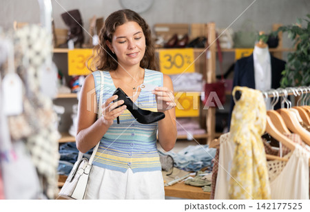 Young woman choosing high heel shoes in store 142177525
