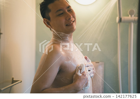 A 40-year-old man enjoying a shower with a smile during his bath time. A 40-year-old man enjoying a shower with a smile during his bath time. 142177625