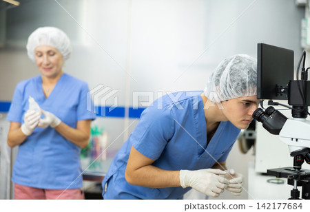 Young veterinarian using microscope to examine blood samples of animal patient Young veterinarian using microscope to examine blood samples of animal patient 142177684