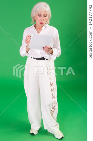 Elderly woman in white clothes takes notes in notebook on green background. Chroma key compositing Elderly woman in white clothes takes notes in notebook on green background. Chroma key compositing 142177742