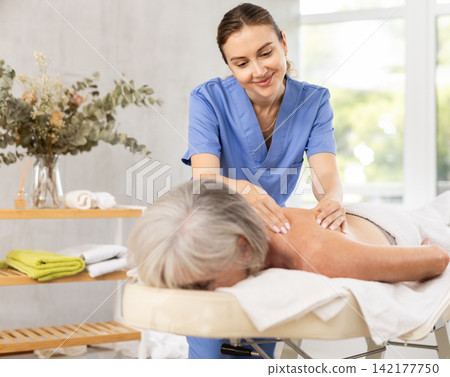Young woman doing back massage to elderly woman 142177750
