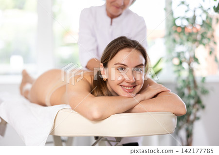Young woman enjoying relaxing massage from professional female masseur Young woman enjoying relaxing massage from professional female masseur 142177785