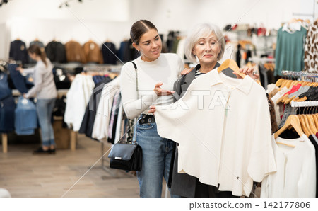 Two satisfied female customers choosing cardigan or jacket in clothing boutique Two satisfied female customers choosing cardigan or jacket in clothing boutique 142177806