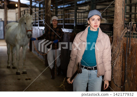 Portrait of young woman in stable with hay pitchfork 142177932