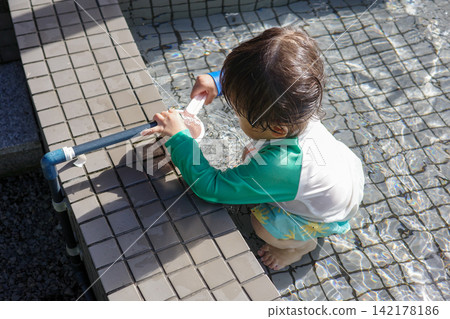 孩子們穿著防曬衣在泳池裡玩耍。 孩子們穿著防曬衣在泳池裡玩耍。 142178186