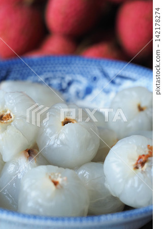 Lychees in a blue bowl with red fruits behind Lychees in a blue bowl with red fruits behind 142178274