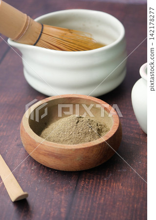 Preparing matcha in a bowl with a whisk on a wooden table Preparing matcha in a bowl with a whisk on a wooden table 142178277