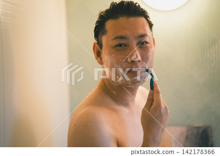 一位40歲的男子在洗澡時微笑著刮鬍子。 一位40歲的男子在洗澡時微笑著刮鬍子。 142178366