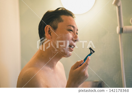 A shower time for a man in his 40s shaving his beard. A shower time for a man in his 40s shaving his beard. 142178368