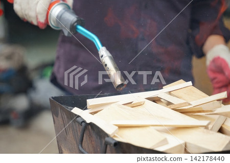 Firewood Being Ignited with a Torch in an Outdoor Fire Pit Firewood Being Ignited with a Torch in an Outdoor Fire Pit 142178440