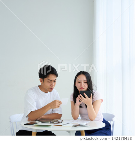 A young man and woman discuss household finances. 142178458
