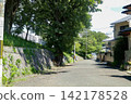 京都住宅區的一條街道，街道兩旁有石牆和樹木。 142178528